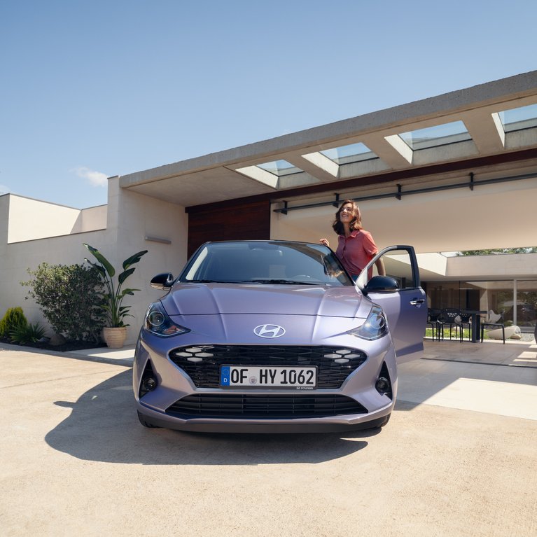 Hyundai Fahrzeug steht vor modernem Wohnhaus, Person steigt ein. Beispielbild für sofort verfügbare Vorführwagen und attraktive Angebote.