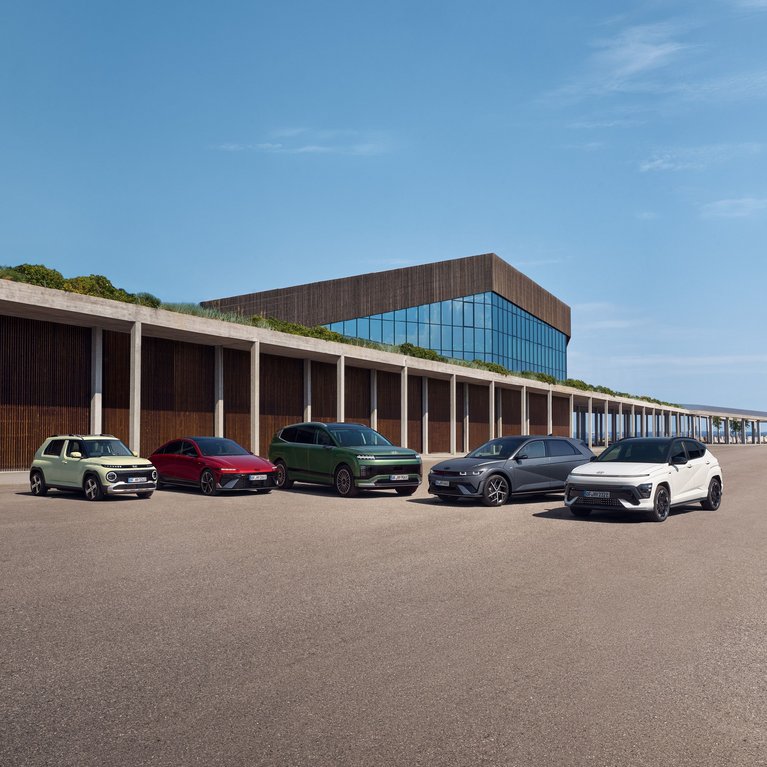 Mehrere Hyundai Modelle vor modernem Gebäude. Die Fahrzeugpalette bewirbt die aktuelle E-Auto Förderung für Hyundai Elektrofahrzeuge und Hybridmodelle.