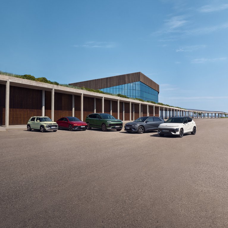 Mehrere Hyundai Modelle vor modernem Gebäude. Die Fahrzeugpalette bewirbt die aktuelle E-Auto Förderung für Hyundai Elektrofahrzeuge und Hybridmodelle.