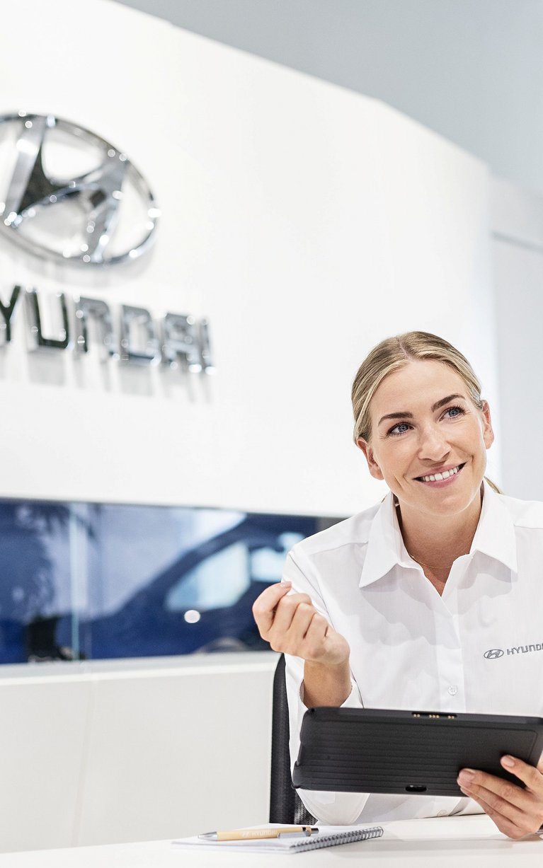 Beratungsgespräch im Hyundai Autohaus Zondler – Mitarbeiterin erklärt Kunden Fahrzeugoptionen am Tablet im Showroom